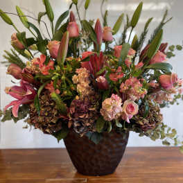 Pink lilies and roses arranged in a dark vase