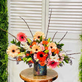 Colorful mixed bouquet in a patterned vase with gerbera daisies and roses