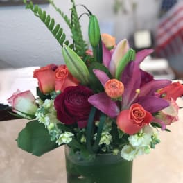 Mixed bouquet of pink roses and purple lilies in a glass vase