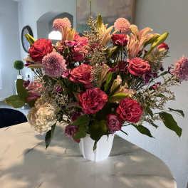 Large pink and peach floral arrangement in a white vase