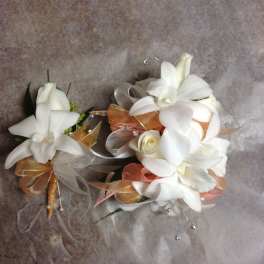 Two white floral corsages with ribbon accents on a textured background
