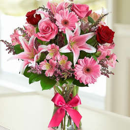 Pink and red mixed bouquet in a glass vase with a ribbon