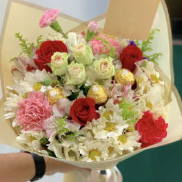 Bouquet of red roses, pink carnations, and white daisies with gold chocolates