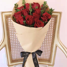 Bouquet of red roses wrapped in tan paper with a black ribbon