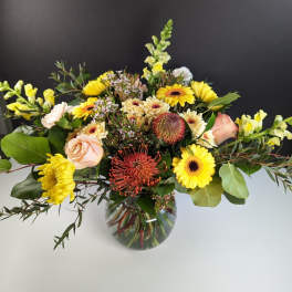 Mixed yellow and peach flowers in a glass vase