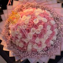 Large bouquet of pink and white roses with a pink ribbon and decorative wrap