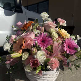 Mixed pink and white flower arrangement in a white basket