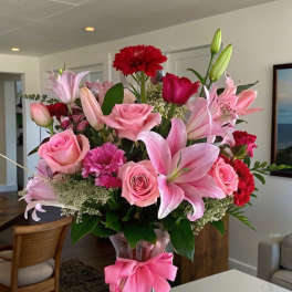 Pink and red mixed bouquet in a clear glass vase with a pink ribbon
