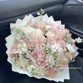 Large bouquet of pink and white flowers wrapped in white paper