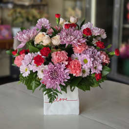 Pink and red mixed bouquet in a white gift bag