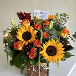 Bouquet of sunflowers and orange roses in a wooden box