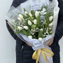 White tulips arranged in a wrapped bouquet with a yellow ribbon