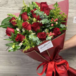 Bouquet of red roses wrapped in burgundy paper with a red ribbon