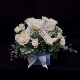 White roses arranged in a blue box with a white ribbon