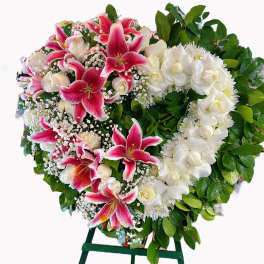 Heart-shaped floral wreath with pink lilies and white roses on an easel