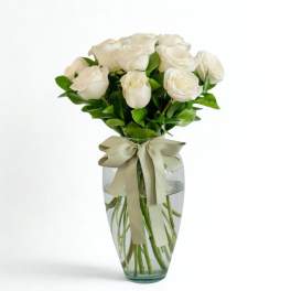 White roses in a clear glass vase with a ribbon bow