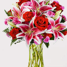 Bouquet of red roses and pink lilies in a clear glass vase