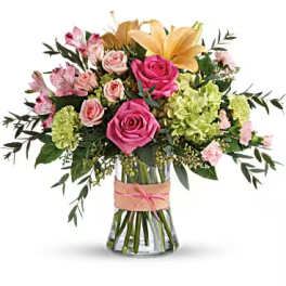 Bouquet of pink roses, lilies, and green hydrangeas in a glass vase