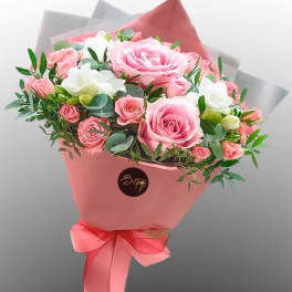 Pink and white rose bouquet wrapped in pink paper with a ribbon