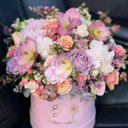 Pink and lavender flower arrangement in a round hat box