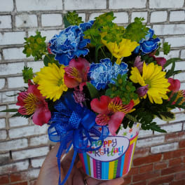 Colorful bouquet in a birthday gift container with a blue ribbon