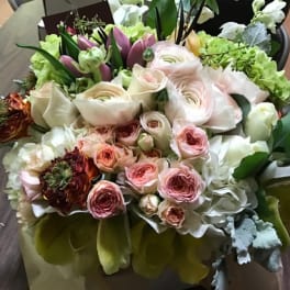 Mixed bouquet of pale pink and white flowers in a wrapped arrangement