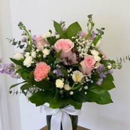 Pink and white mixed bouquet in a glass vase with a white ribbon