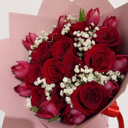 Bouquet of red roses and pink tulips wrapped in blush paper