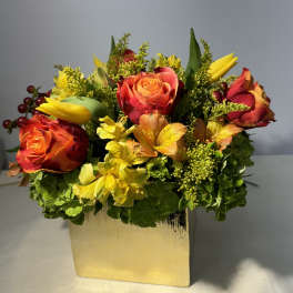 Orange and red roses with yellow flowers in a gold vase