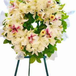 White floral wreath with pink accents on a stand