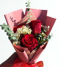 Bouquet of red roses with white filler flowers and pink wrapping