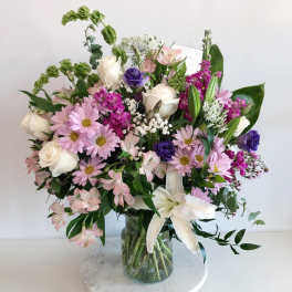 Mixed bouquet of pink, white, and purple flowers in a glass vase