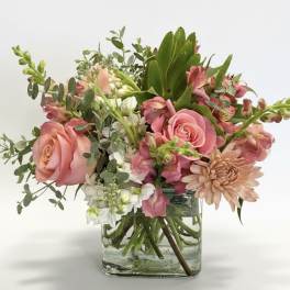 Pink roses and mixed flowers arranged in a clear glass vase