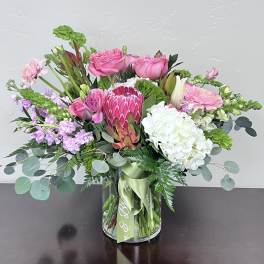 Pink and white mixed bouquet in a glass vase with a green ribbon
