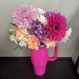 Bouquet of pink, purple, white, and peach flowers in a bright pink tumbler