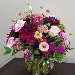 Round arrangement of pink and purple mixed flowers in a clear glass bowl vase