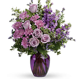 Lavender roses and purple flowers in a purple glass vase