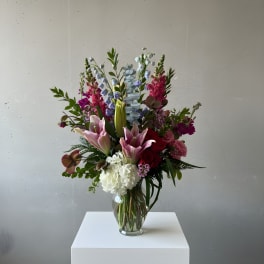 Tall mixed bouquet in a clear glass vase with pink lilies and white hydrangea
