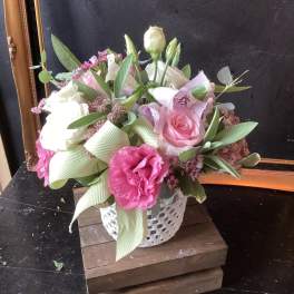 Pink and white flower arrangement in a white vase with ribbon