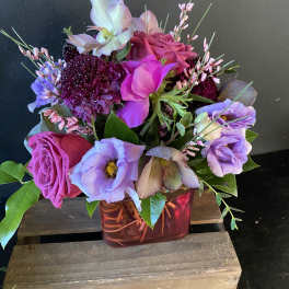 Mixed bouquet of pink, purple, and lavender flowers in a red glass vase