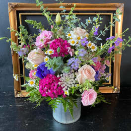 Mixed pink, purple, and white flowers in a ribbed metal container