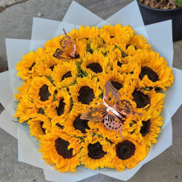 Bouquet of yellow sunflowers wrapped in pale paper with butterfly picks