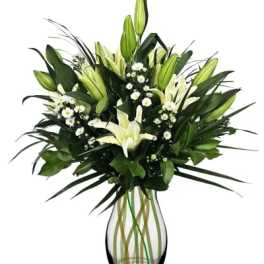 White lilies and small white daisies in a clear glass vase