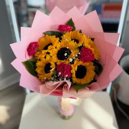 Bouquet of sunflowers and pink carnations wrapped in pink paper