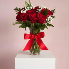 Red roses in a glass vase with a red ribbon