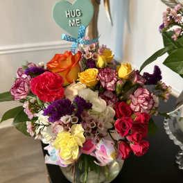Mixed bouquet in a glass vase with a "HUG ME" heart pick