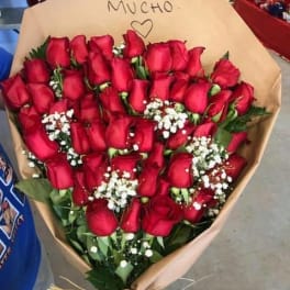 Bouquet of red roses wrapped in tan paper with a handwritten note