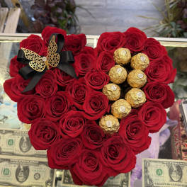 Heart-shaped red rose arrangement with gold-wrapped chocolates and a black ribbon bow