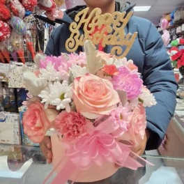 Pink and white flower arrangement with a gold "Happy Birthday" topper