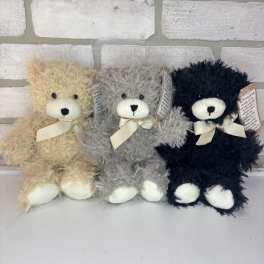 Three plush teddy bears in beige, gray, and black with ribbon bows